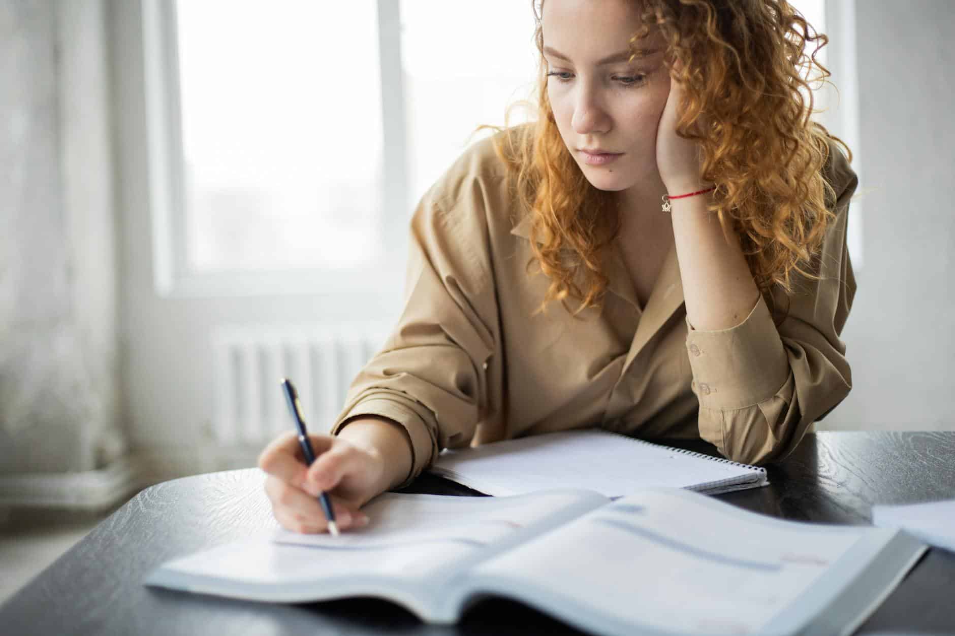 crop clever woman writing in book